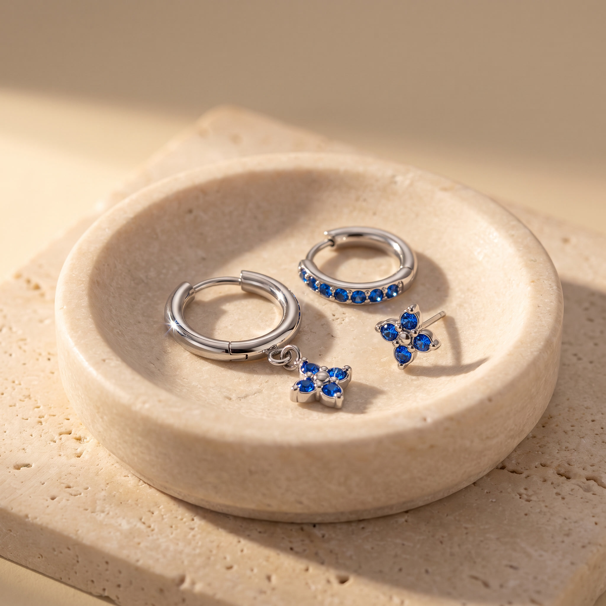 Myrtle Clover Stack Earrings in Silver displayed on travertine